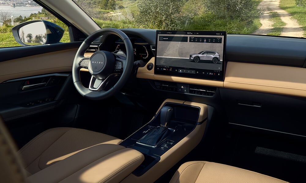 Vue à partir du siège passager avant du Mazda CX-5 montrant le volant et l’écran tactile central.